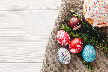 happy Easter concept. stylish painted eggs and easter cake on rustic wooden background with spring flowers, top view. seasons greeting card. space for text. modern flat lay