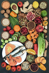 Health food concept with fresh fish, fruit,vegetables, seeds, nuts, pulses, cereals, grains, pollen grain, spices and herbs. Super food high in omega 3 fatty acids, protein, antioxidants and vitamins 