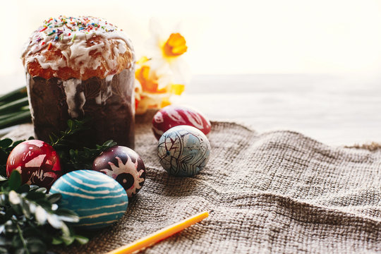 happy Easter concept. stylish painted eggs and easter cake on white rustic wooden background with spring flowers and candle. seasons greetings. space for text. modern easter image