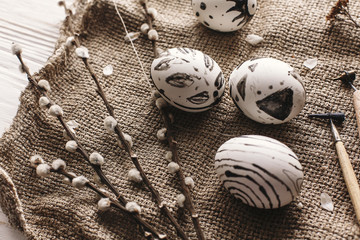 stylish easter painted eggs black and white colors at rustic wooden background with willow branches. happy easter greeting card. modern easter eggs top view. rural easter image