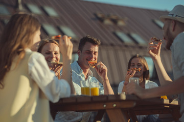 Young friends eating pizza outdoors
