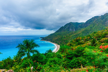Fototapeta na wymiar picturesque natural wild landscape with rocky mountains overgrown dense green jungle tree, palm and clear azure water of sea ocean