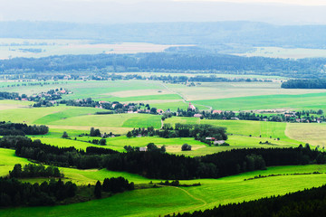Fototapeta na wymiar Misty valley of Broumovsko in Czech Republic with fields and green meadows. Scenic picturesque countryside landscape. Vast panorama of Viznov village in the Sudetes. Aerial view.