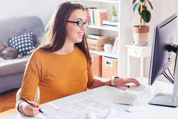 Beautiful female designer or architect  drawing and working on a computer at home office, remote