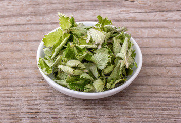 herbal tea from strawberry leaves / Porcelain bowl with dried strawberry leaves on a wooden background