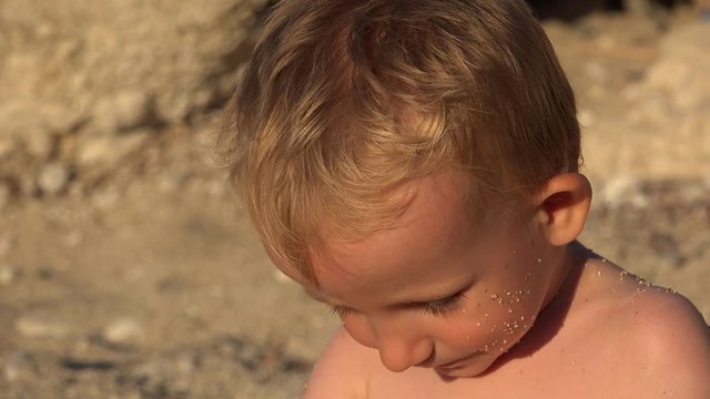 Funny little child portrait on seashore smiling, pointing with finger 4K