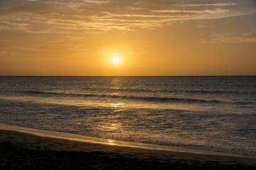 Fototapeta na wymiar Setting sun reflecting over a calm still ocean