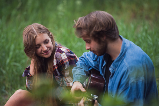 Man romantically serenades his girlfriend around the campfire