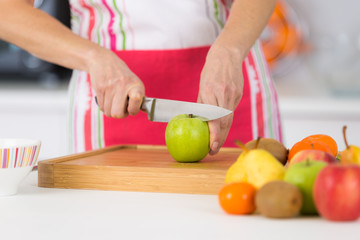 Obraz na płótnie Canvas close-up on mature female hands slicing apples on chopping board