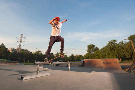 Teenager performing tricks with skateboard on railing in skate park