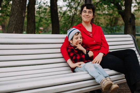 Older sister sitting on the bench with her brother with infant cerebral paralysis