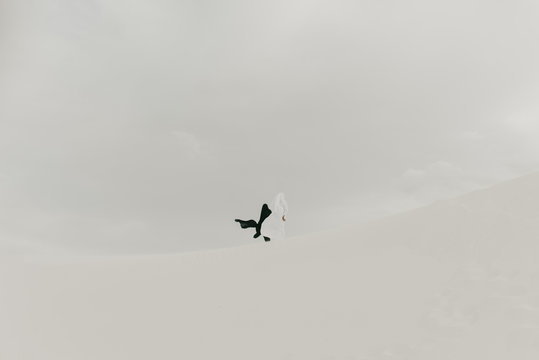 Black versus white concept of two opposing people draped in contrasting fabrics in the desert