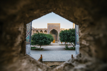 uzbek mosque seen through a stone hole, registan, samarqand, uzbekistan