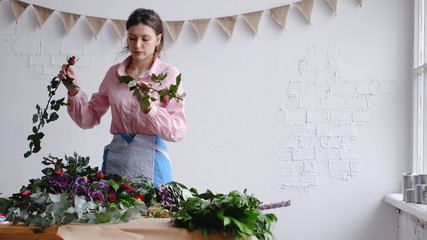 Concentrated young female florist creating a floral composition, inspect flowers