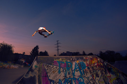 Male skater jumping in midair on ramp in skate park
