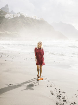 Dog running on beach and owner walking