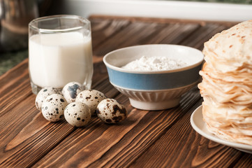 Ingredients for preparation of pancakes, on wooden background.
