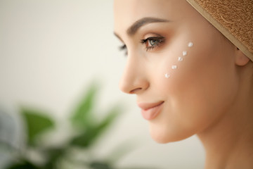 Skin care. Studio shot of beautiful young woman applying moisturizer cream onto her face