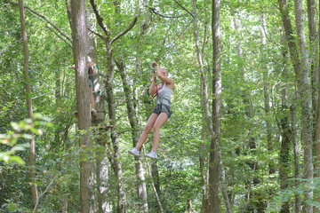 Naklejka na ściany i meble woman suspended on forest adventure course