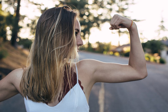 Profile of a beautiful teenage girl flexing her bicep