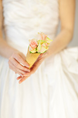 Obraz na płótnie Canvas woman bride hands holding rose flowers in an ice cream cone, sensual studio shot can be used as background