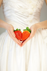 Obraz premium woman bride hands holding some strawberries in her hands, sensual studio shot can be used as background