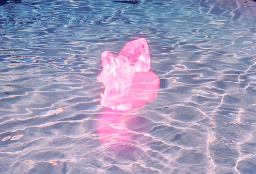Pink crystal floating on blue pool of water