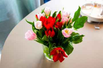 Bouquet of tulips in the vase on the round table next to the window