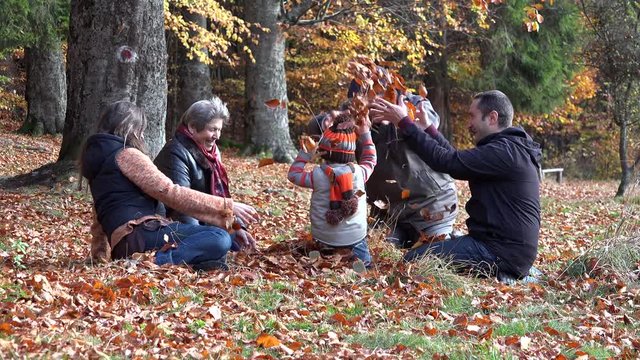 Child, parents and grandparents playing together,  autumn leaves, happy family
