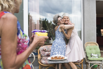 Playful senior women exchanging gifts during birthday party