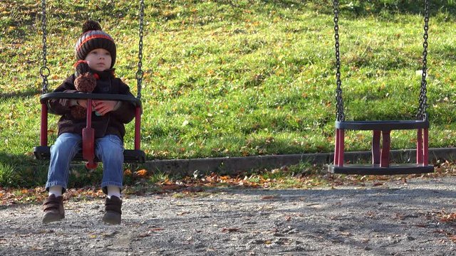 Swing with a sweet child near an empty swing, single boy waiting a brother