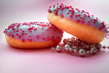 Macro shoot of 2 donuts covered with blue glaze.and pink powder for baking with silver beads