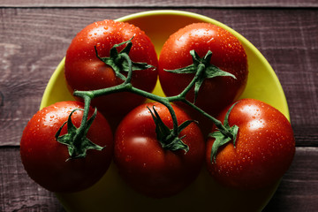 Freshly picked ripe tomatoes on a wooden retro table. Preparations for cooking. Vegetables lie on bright plates. Close up. Modern style