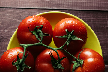 Freshly picked ripe tomatoes on a wooden retro table. Preparations for cooking. Vegetables lie on bright plates. Close up. Modern style