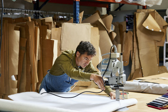 Worker Cutting Fabric With Machine In Sofa Workshop