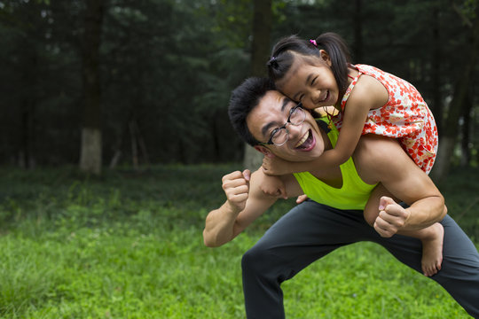 Asian man holding his little girl outdoor in the park