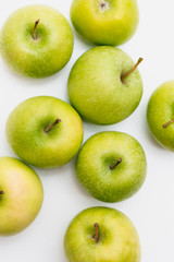 Flatlay with eight fresh, green-yellow Golden Smith or Granny Smith apples on white background