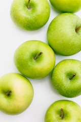 Flatlay with seven fresh, green-yellow Golden Smith or Granny Smith apples on white background