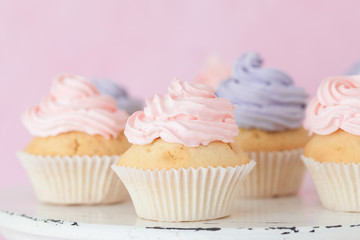 Cupcakes with pink and violet buttercream standing on pastel pink background.