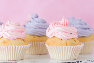 Cupcakes with pink and violet buttercream standing on pastel pink background.