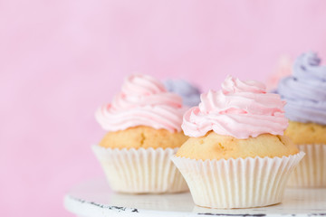 Cupcakes with pink and violet buttercream standing on pastel pink background.