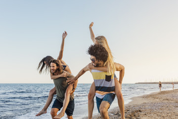 Friends doing a piggyback race at the beach