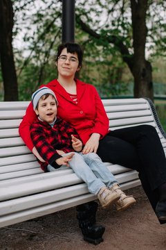 Older sister sitting on the bench with her brother with infant cerebral paralysis