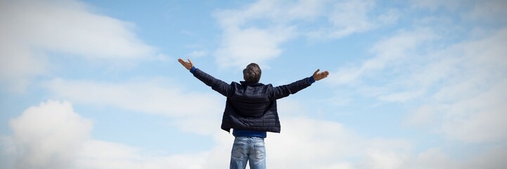 Composite image of rear view of a man raising his arms up