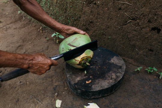 anonymous male chopping coconut with big blade