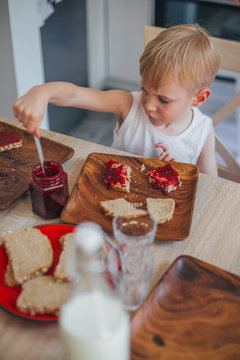 Boy spreading jam on bread at breakfast