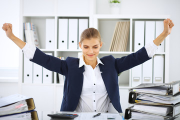 Happy business woman or female accountant having some minutes for coffee and pleasure at working place