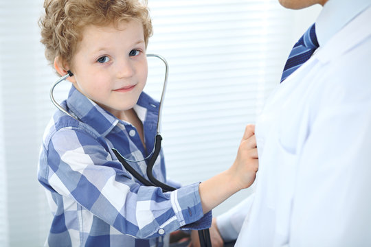 Doctor and child patient. Little boy play with stethoscope while physician communicate with him. Children's therapy and trusting relationship in medicine concept