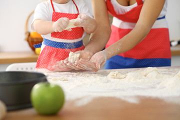 Mother and her cute daughter hands prepares the dough on wooden table. Homemade pastry for bread or pizza. Bakery background