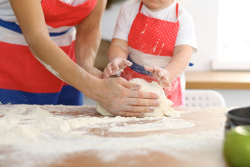 Mother and her cute daughter hands prepares the dough on wooden table. Homemade pastry for bread or pizza. Bakery background